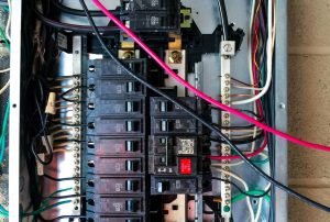 An open electrical panel with multiple circuit breakers and visible wiring, showing a mix of connected wires including pink, white, and black. The image highlights the complexity and safety considerations involved in electrical panel setups. electrical panel, circuit breaker box, electrical safety, wiring inspection, panel upgrade, electrical repair services, Sacramento electricians, Roseville electrical maintenance, Rocklin electrical services, Folsom home safety, Auburn electrical panel replacement, Citrus Heights circuit management