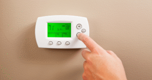 hand adjusting digital thermostat to control home air conditioning system