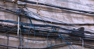 tangled electrical wires on wall indicating potential faulty wiring hazard