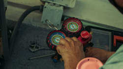 An HVAC technician checking the Freon in an air conditioner.