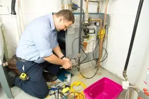 technician servicing residential furnace during heating system maintenance